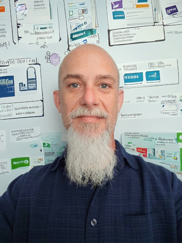 Picture of David Villers in front of wall of wireframes and sketches